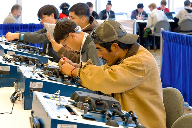 Large group of auto technicians in competition working on project