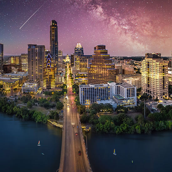 2025 Texas Economic Impact Report; A vibrant city skyline at twilight with illuminated skyscrapers under a starry sky. A bridge crosses over a calm river, conveying a tranquil yet dynamic urban scene.